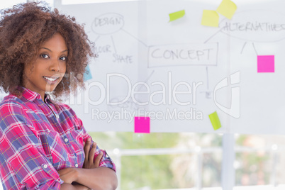 Happy woman with arms crossed in front of whiteboard