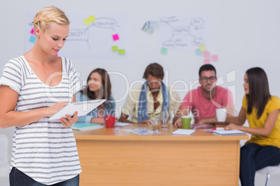 Editor using tablet pc as team works behind her