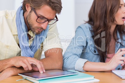 Editor using tablet at meeting as colleague is talking