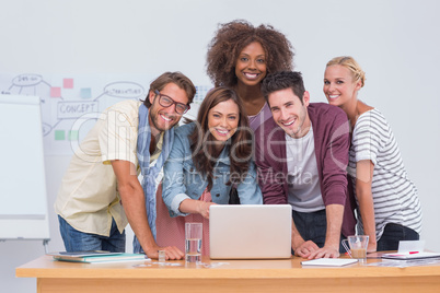Creative team standing at desk with laptop