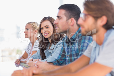 Creative team sitting in a line with one woman smiling