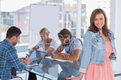 Team having meeting with one woman standing and smiling at camer