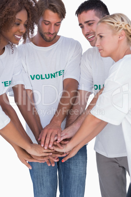 Smiling volunteers putting hands together