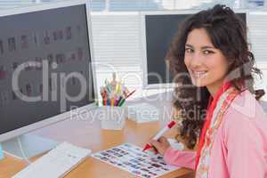 Editor marking the contact sheet and smiling at camera