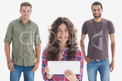Stylish friends smiling at camera with one holding tablet