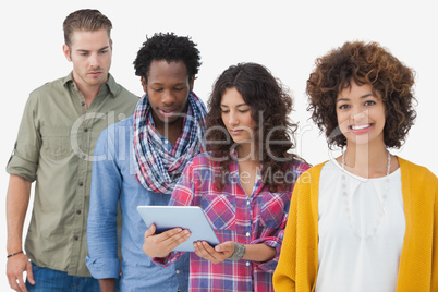 Four stylish friends in row with three looking at tablet