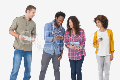 Four stylish friends looking at tablet and holding phones