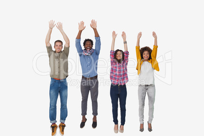 Four stylish friends smiling at the camera and jumping