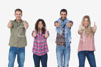 Fashionable friends looking at camera and giving thumbs up