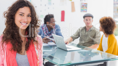 Smiling woman with creative team working behind