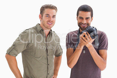 Stylish friends smiling with one holding camera