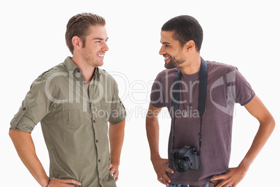Stylish friends smiling at each other with one holding camera