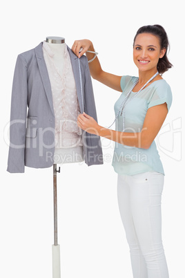 Fashion designer measuring blazer lapel on mannequin and smiling