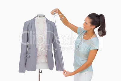Fashion designer measuring blazer sleeve on mannequin