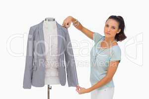 Fashion designer measuring blazer sleeve on mannequin and lookin