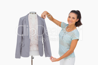 Fashion designer measuring blazer sleeve on mannequin and smilin