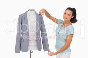 Designer measuring blazer sleeve on mannequin