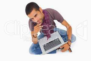 Thoughtful man sitting on floor using laptop