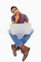 Thinking man sitting on floor using laptop