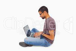 Man wearing glasses sitting on floor using laptop