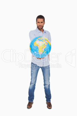Serious man holding out a globe