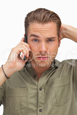 Puzzled man on the phone looking at camera