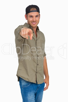 Man smiling and wearing baseball hat backwards and pointing