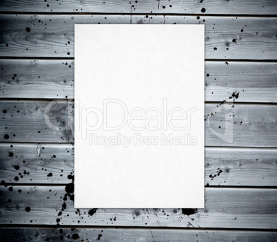 White poster pin against a wooden boards wall