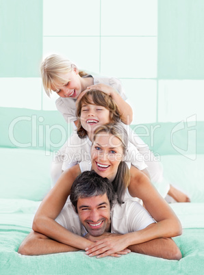 Smiling family piled on top of dad