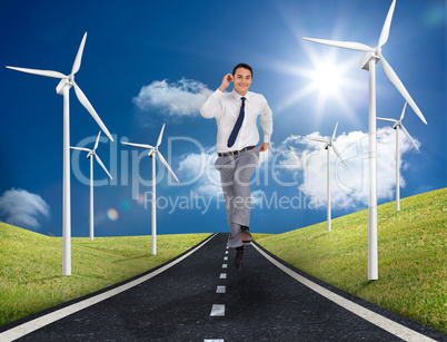 Businessman running on a road next to windmills