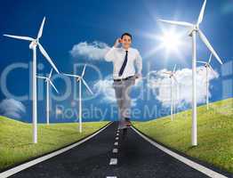 Businessman running on a road next to windmills