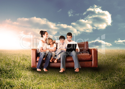 Happy family using the laptop in a field