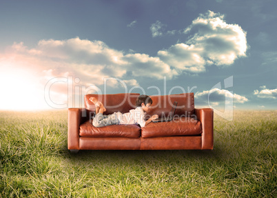 Child using laptop on couch in field