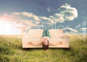 Woman sitting upside down on couch in field