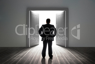 Businessman looking at door showing bright light