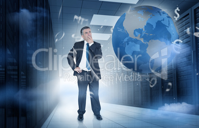 Businessman standing in data center with currency graphics and e