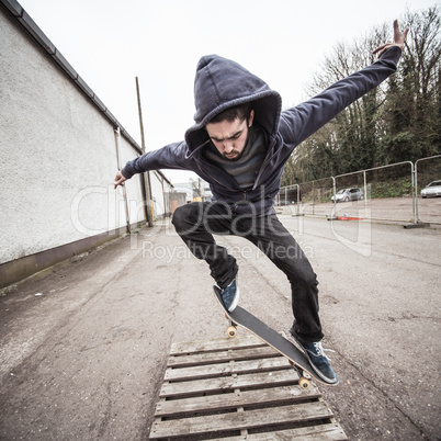 Skater doing ollie over wooden crate