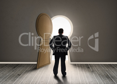 Buisnessman looking at keyhole shape door revealing light