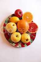 plate with orange grapefruit and apples