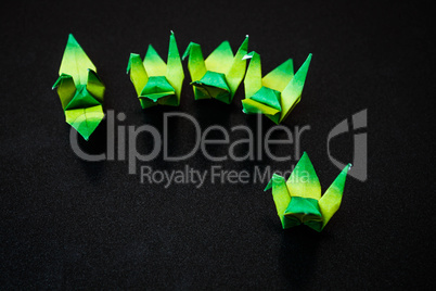 A group of green paper birds on dark background