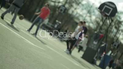 Teenagers playing basketball in a city park. Blured