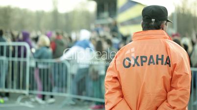 Back of a security guard in front of blurred crowd