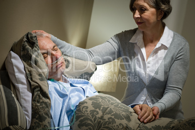 Sick lying senior man and caring wife