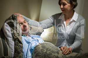 Sick lying senior man and caring wife
