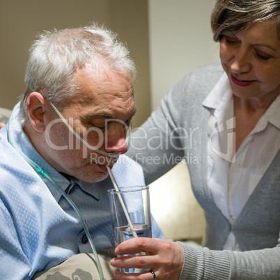Nurse helping senior sick man with drinking