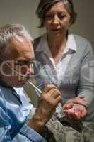 Caring senior wife holding drugs for husband