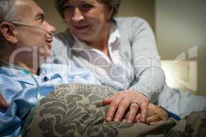 Elderly couple holding hands lying in bed