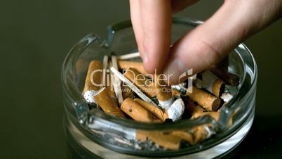 Hand putting cigarette out in ashtray