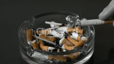 Hand tipping ash from cigarette into ashtray