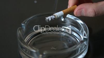 Hand tipping ash into empty ashtray